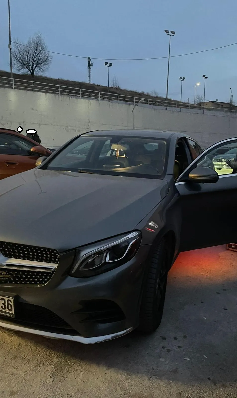 Akşam saatinde otoparkta kapısı açılmış gri Mercedes