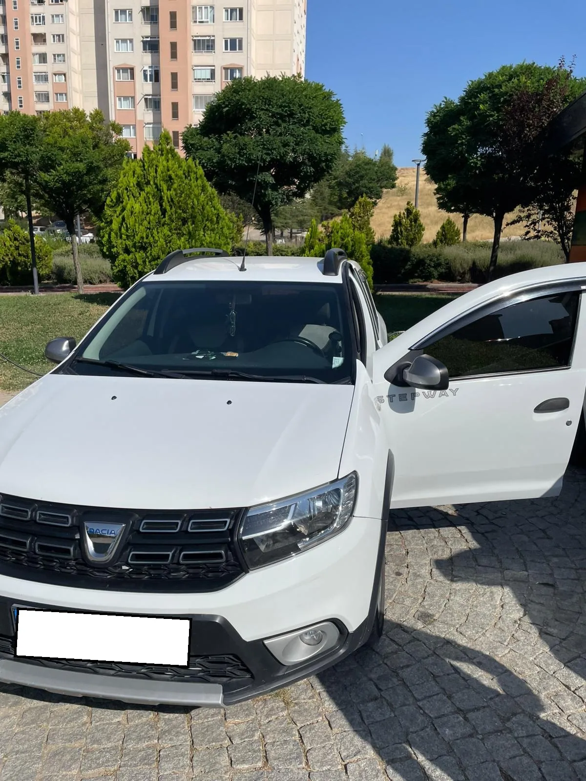 Site içinde kapıları açılmış beyaz Dacia Sandero Stepway