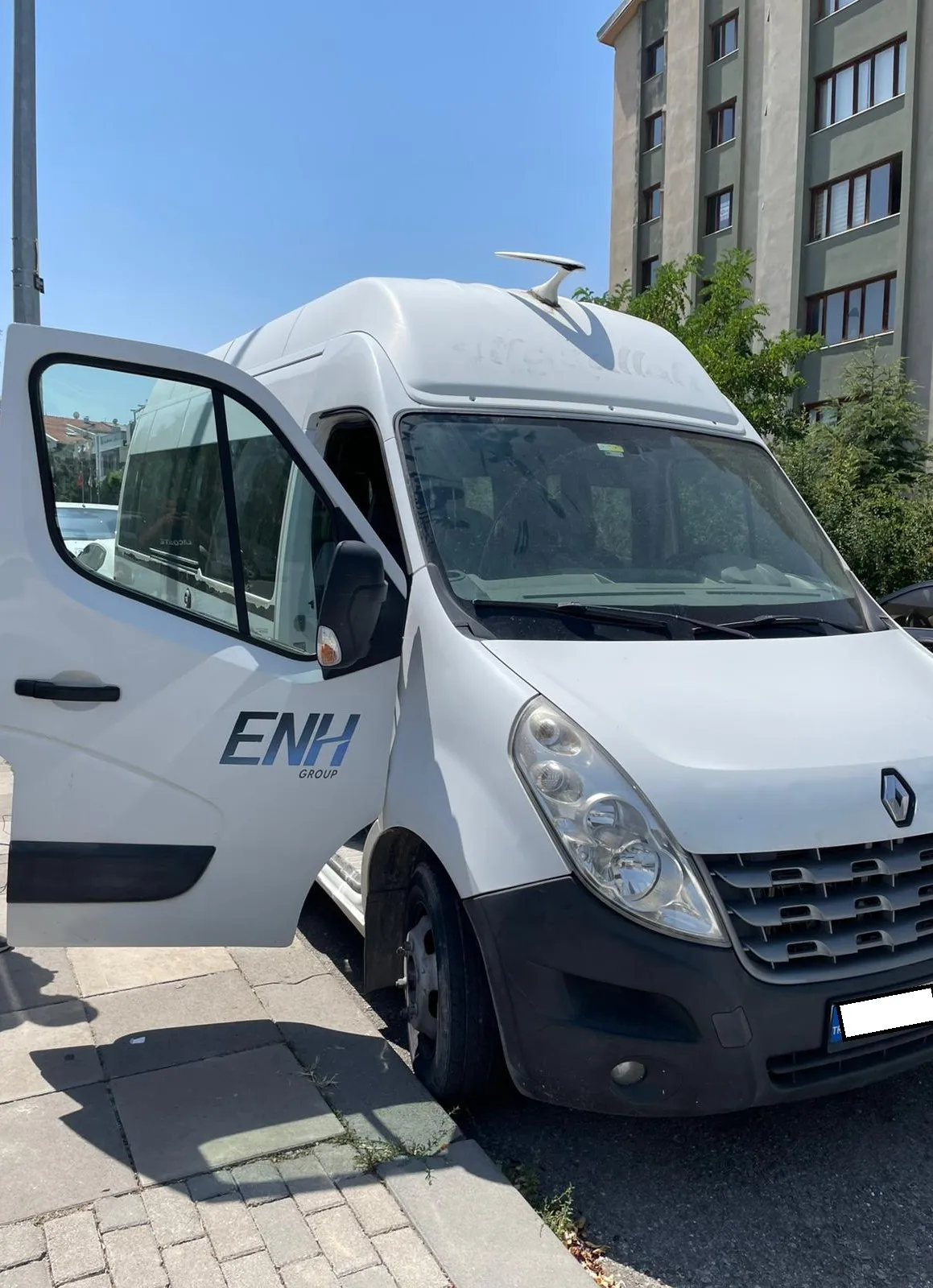 Cadde kenarında sürücü kapısı açılmış beyaz Renault Master minibüs